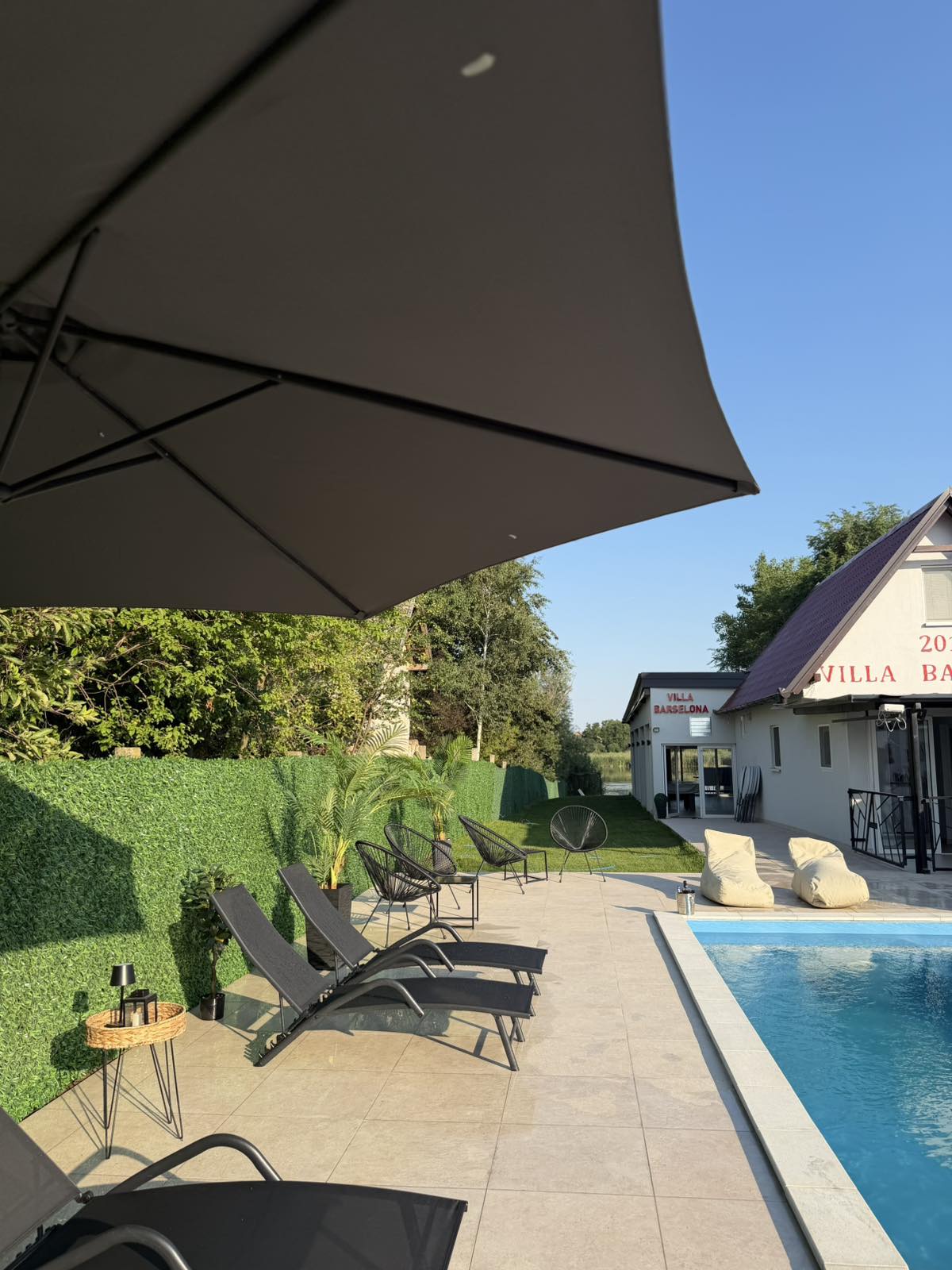 Terasa Villa Barselona sa suncobranom, ležaljkama i pogledom na Tisu